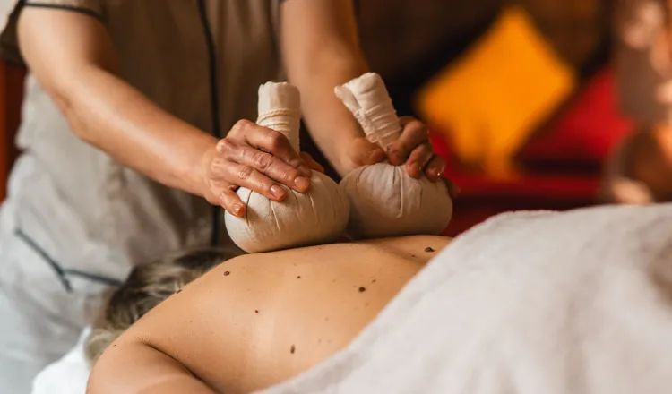 Frau bei einer ayurvedischen Kräuterstempel-Massage im Wellnessurlaub im Grand Hotel Binz mit vielen Ayurveda Angeboten.