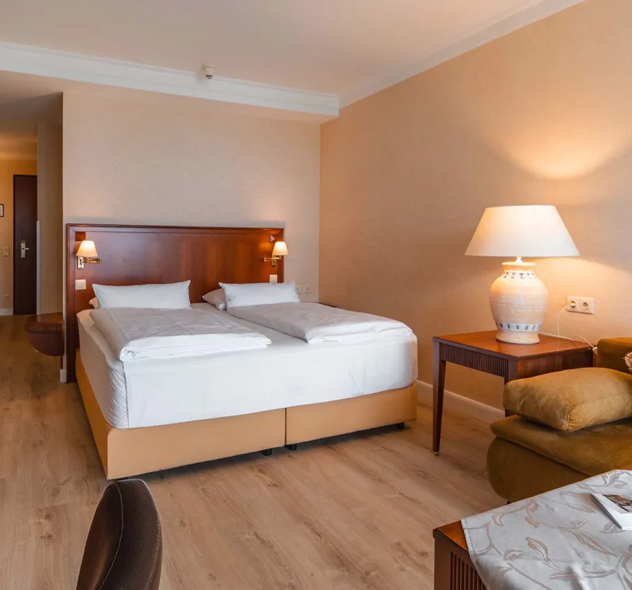 Komfortables Baltic Deluxe Zimmer im Grand Hotel Binz mit gemütlicher Sitzecke, Balkon und Ostseepanorama.