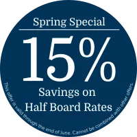 Round dark blue promotional badge in englisch featuring the text “Spring Offer”, “15% Discount on Half Board”, and a note stating that the offer is valid until end of June and cannot be combined with other offers.