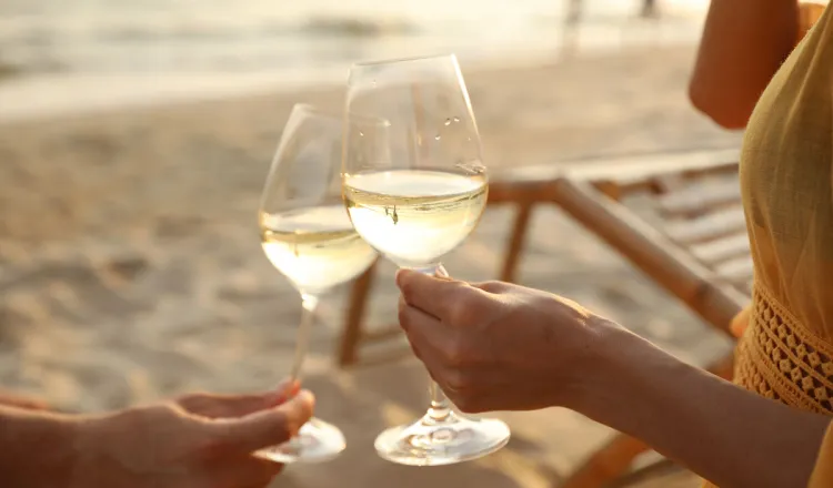 Gästepaar beim Anstoßen am Strand vor dem Grand Hotel Binz – Symbol für Green Stay und gemeinsame Umweltaktionen
