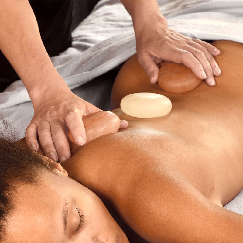 Wellnessbehandlung mit Himalaya-Salzsteinen auf dem Rücken zur Muskelentspannung.
