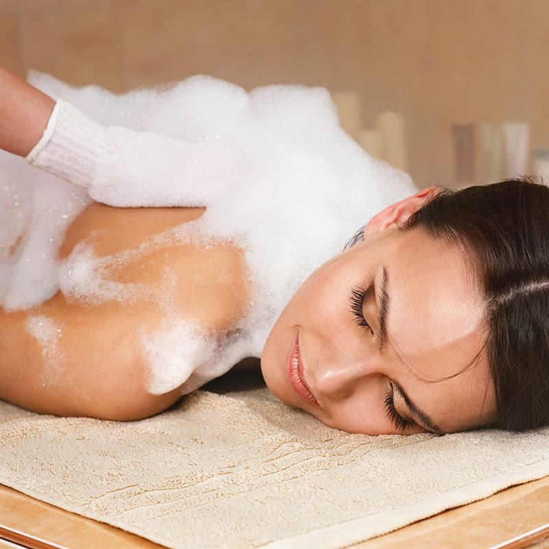 Orientalische Körperreinigung mit Seifenschaum, Spezialhandschuh und Peeling auf der warmen Steinliege im Hamam.