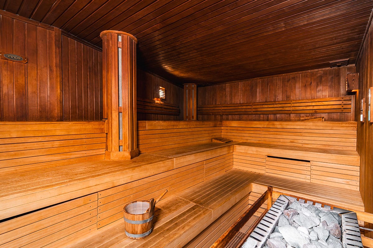 Klassische finnische Sauna mit Holzverkleidung, Saunakübel und heißen Steinen für Aufgüsse