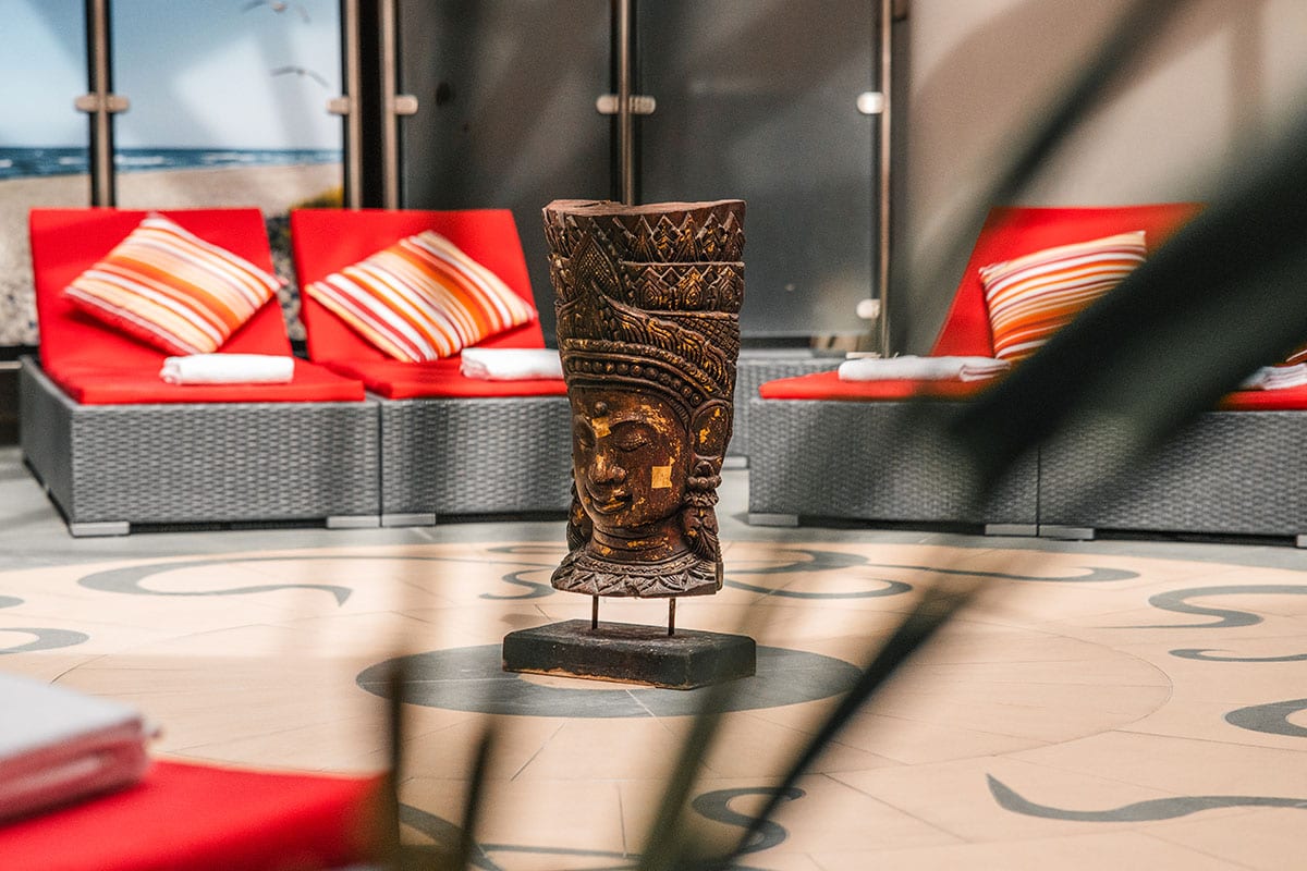 Asiatisch inspirierte Figur als Dekoration im Wellnessbereich mit Strandmotiv im Hintergrund