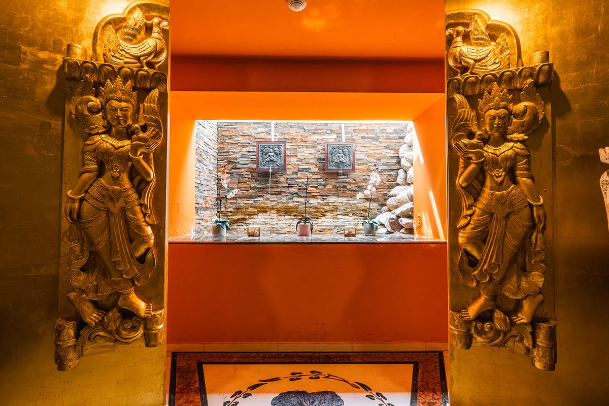 Goldene Wandfiguren flankieren die Sicht auf eine Natursteinwand mit Steindekor
