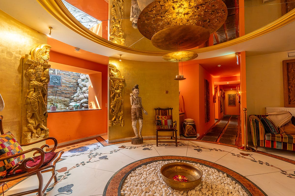 Wartebereich im Thai-Bali Spa mit Skulpturen, Mosaikboden und goldenen Wänden